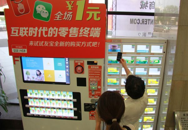  资料图片：在中国互联网大会的自动贩售机前参会者体验用微信扫描，通过在线支付购买物品。（新华社）