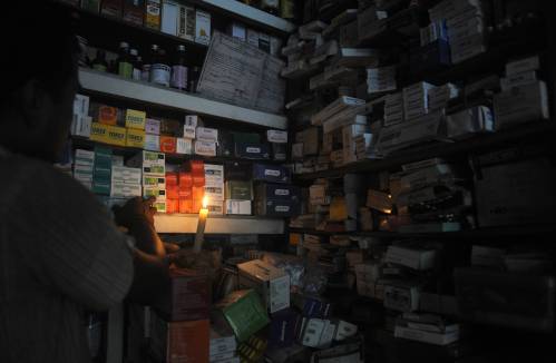  圖為在印度西里古里，一位藥店店員借著燭光尋找藥品。新華社/法新