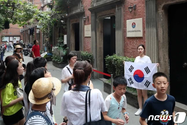 　14日，一名韩国女游客在临时政府旧址前举韩国国旗留念。（图源：news 1）