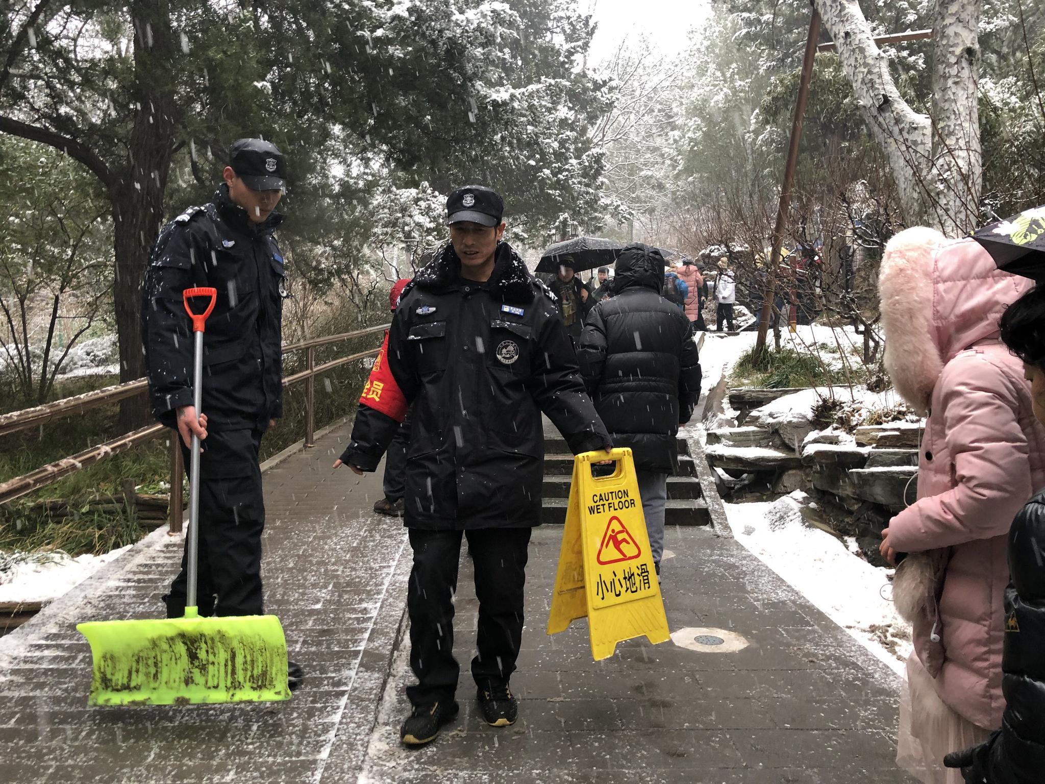 上山路面湿滑，有工作人员清理雪水和冰碴，提醒游客注意安全。新京报记者 张静姝 摄