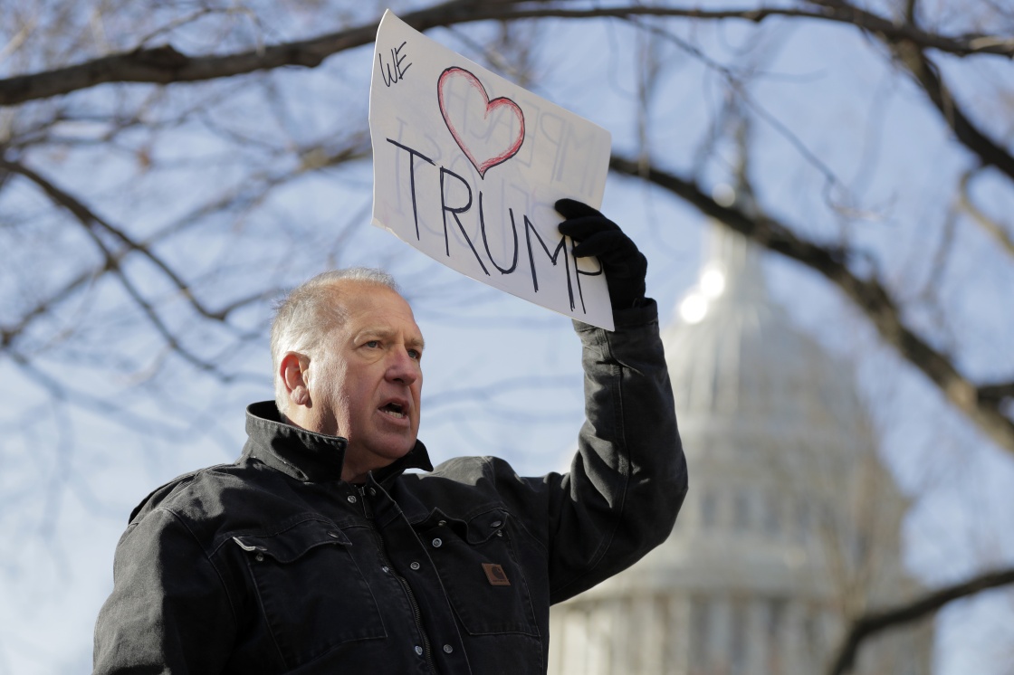  一名示威者在國會大廈外手持反對彈劾總統川普的標語。 