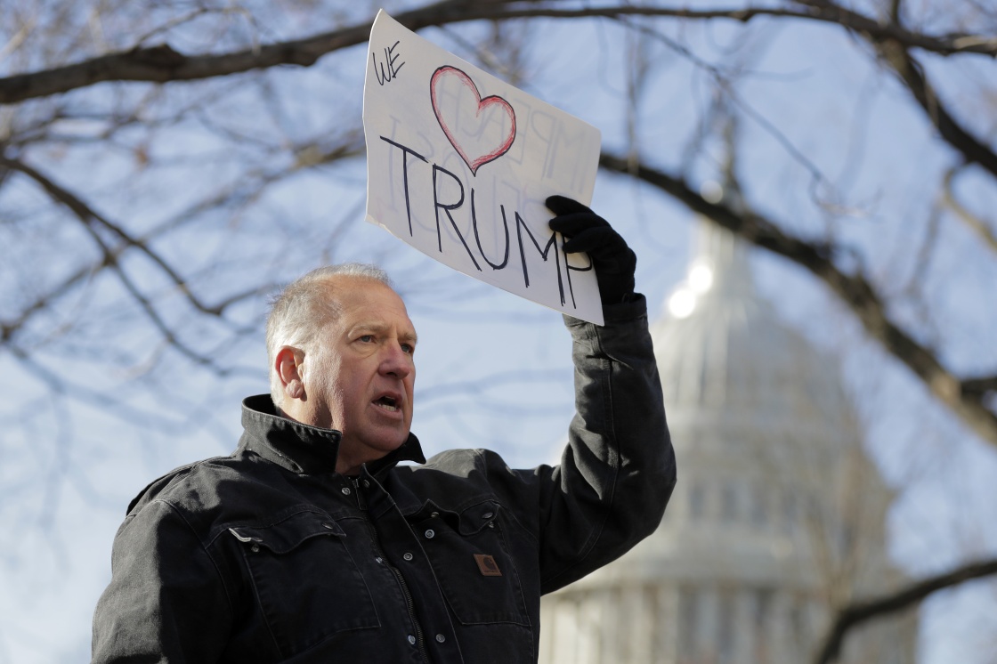  一名示威者在國會大廈外手持反對彈劾總統川普的標語。 