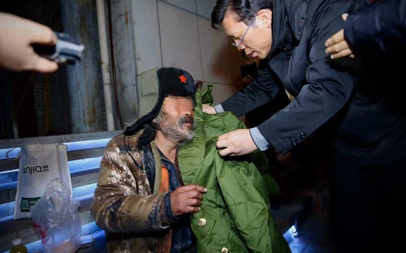 该乞讨老人不愿跟随前往救助站,救助人员从救助箱中取出军大衣送给