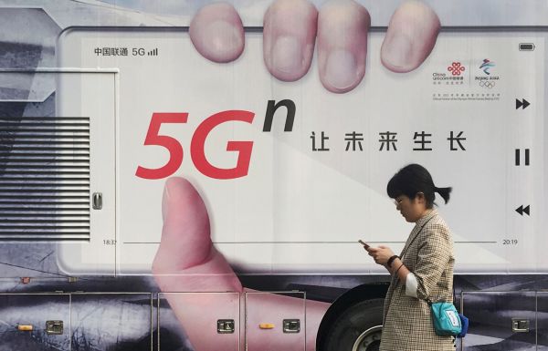 资料图片：北京，一名女子走过一辆印有5G广告的车辆。（路透社）