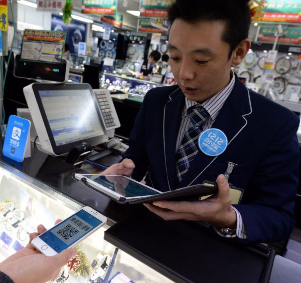 资料图片：日本东京，一家商场的店员使用支付宝为顾客结账。（新华社）