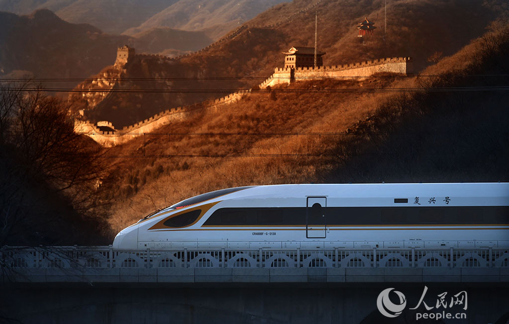 12月30日,一辆复兴号智能动车组在北京居庸关长城下一闪而过.