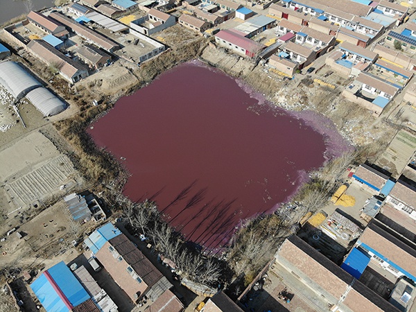 一个水体呈红色方形坑塘被周围房屋包围。  本文图片均来自绿领环保组织
