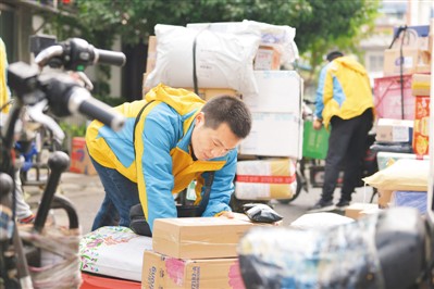 11月13日，在江苏南京，快递员柳礼刚把包裹搬运到电动车上。 　　方东旭摄（人民图片）