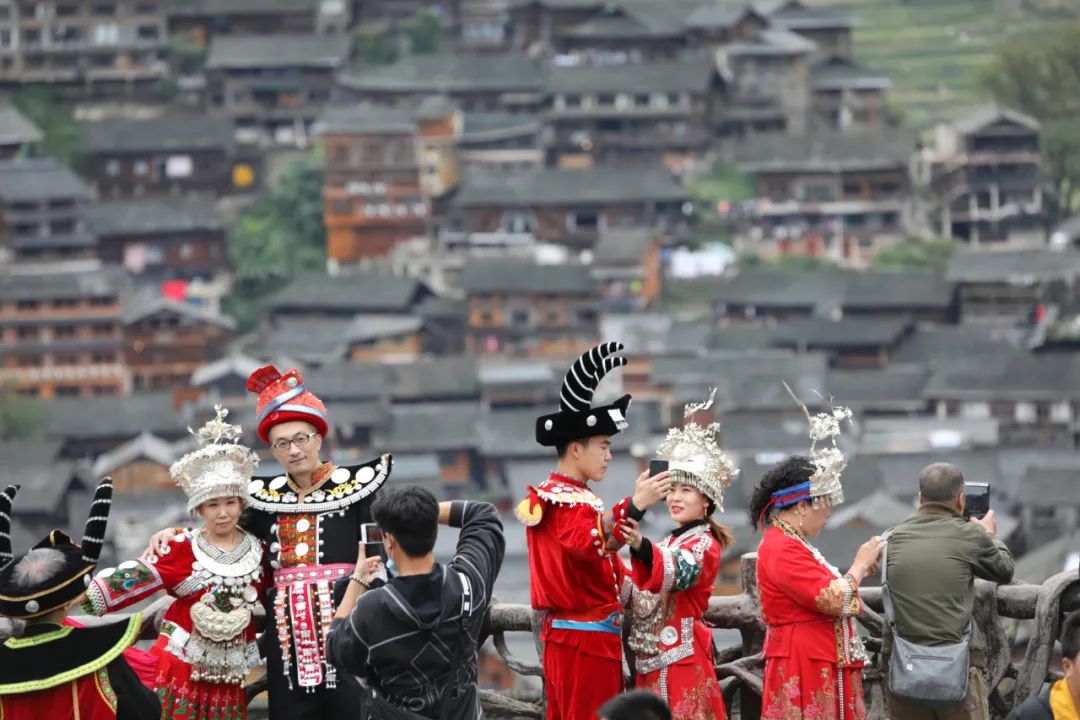▲10月7日,游客穿着民族服装在贵州省雷山县西江千户苗寨不益看景台拍照留念。新华社发(林世康 摄)