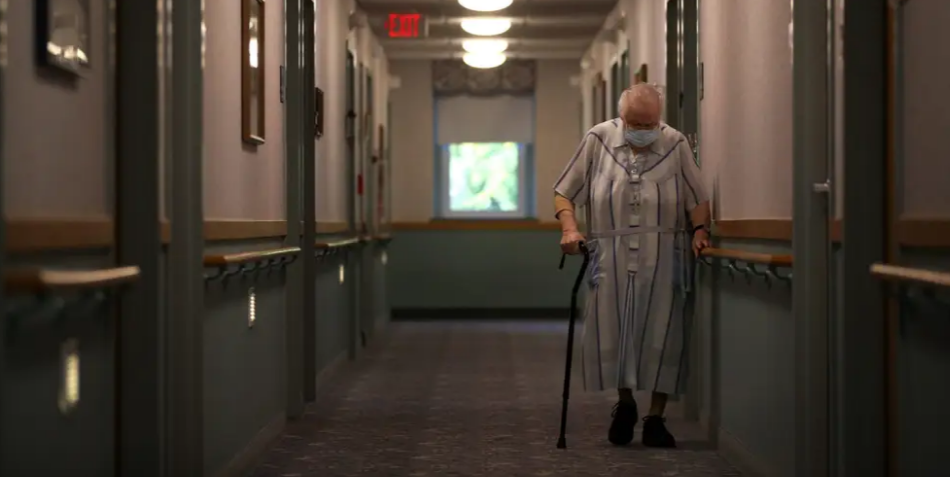 美国一家养老院中，一位戴口罩的老人走过。（图源：Getty）