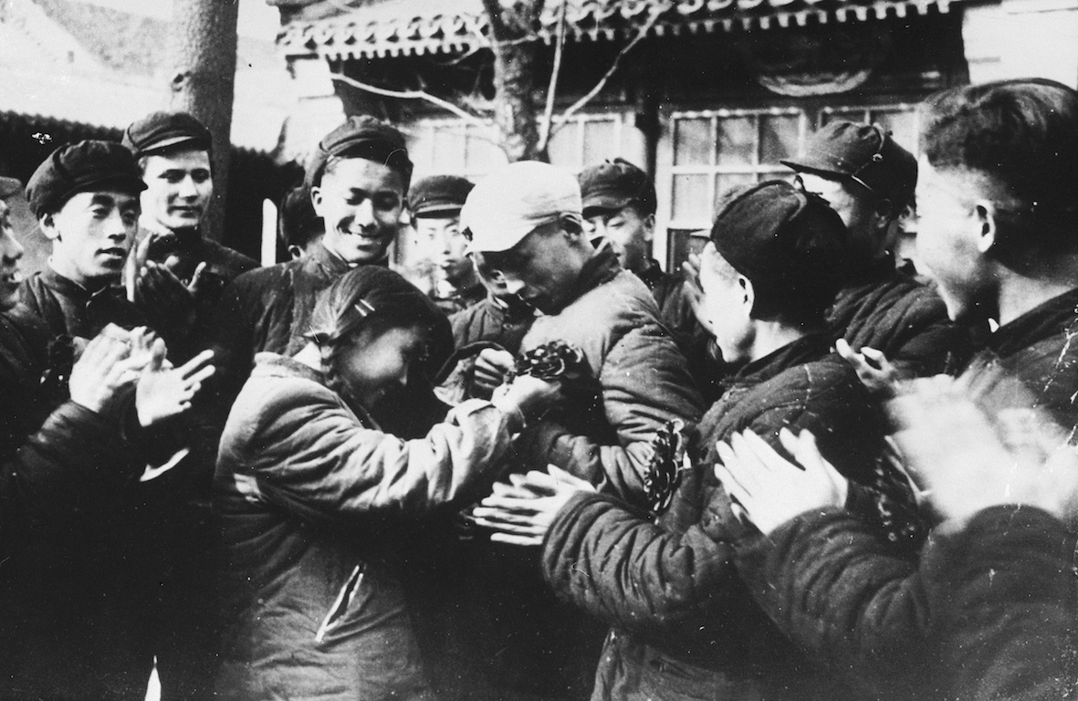 △1950年12月，北京，报名参加抗美援朝的学子被同学们戴上光荣花。