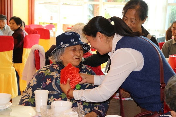 在敬老节之际，建水县开展为老人祝寿活动，工作人员耐心细致为长寿老人佩戴祝寿红花，为老人送上美好的祝福，唱响新时代敬老爱老最强音。（李云菊  摄）