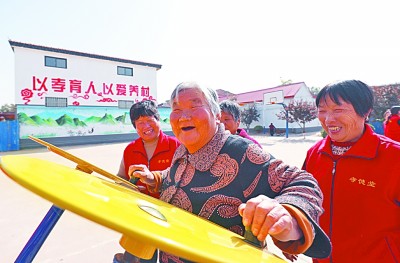     志愿者在南中堡村广场陪老人健身。刘学维摄/光明图片