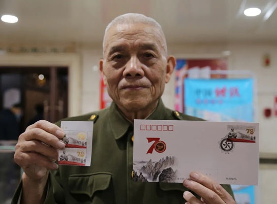 志愿军通信兵杨启国展示纪念邮票和首日封。骆延峰 摄