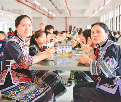  2020年10月13日，贵州省册亨县高洛街道第一小学搬迁子女在学校食堂吃“营养餐”，值班老师在陪餐。梁兴星摄（人民视觉）