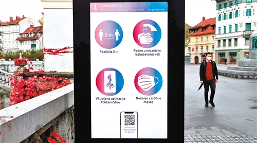 图为10月27日，在斯洛文尼亚首都卢布尔雅那，行人经过一块宣传防疫措施的电子告示牌。新华社记者 彭立军摄