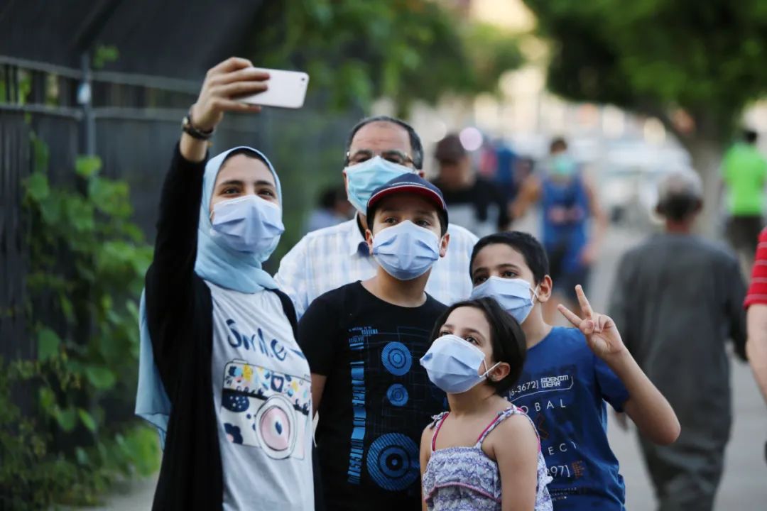 6月12日,在埃及首都开罗,戴口罩的行人在街上自拍.