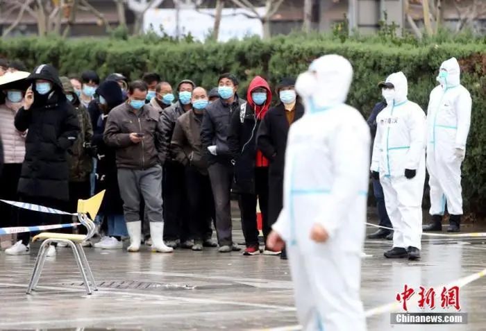 11月21日,受新冠肺炎疫情影响,天津市滨海新区对辖区内全体居民进行大规模核酸检测筛查。图为民众等待核酸检测取样。中新社记者 张道正 摄