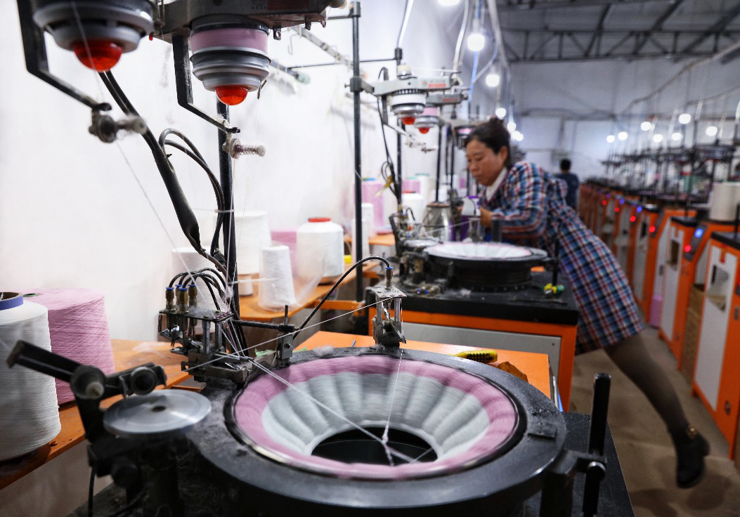 ▲沐洁之家的生产线，机器直接纺织出各种型号的马桶垫。图为工人在调试机器。（摄影：杨子）