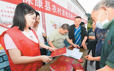 今年8月以来，湖北省襄阳市保康县农村不动产确权登记发证工作全面启动。图为工作人员正在向保康县龙坪镇川山村村民发放农村房地一体不动产权证书。陈泉霖摄（人民视觉）