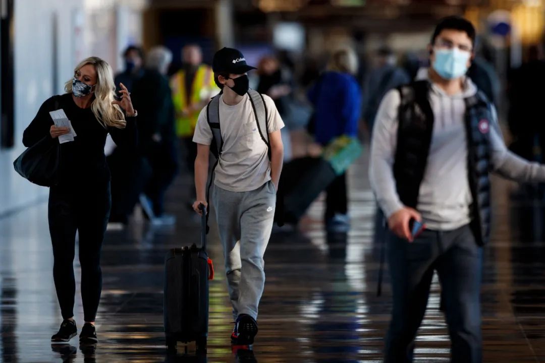 11月24日,戴口罩的旅客走在美国弗吉尼亚州阿灵顿的里根国家机场.