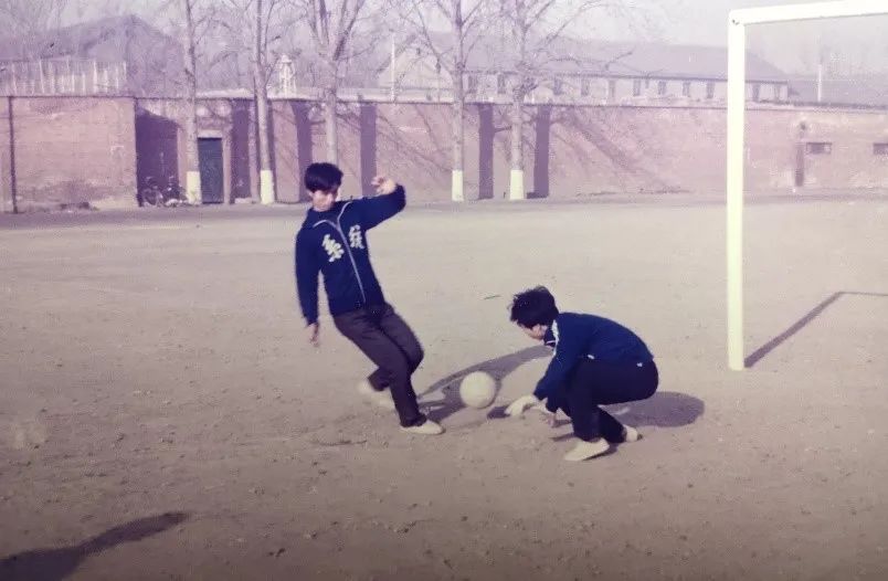 图为黄晋阳老师（左）在操场上踢足球（1985年）