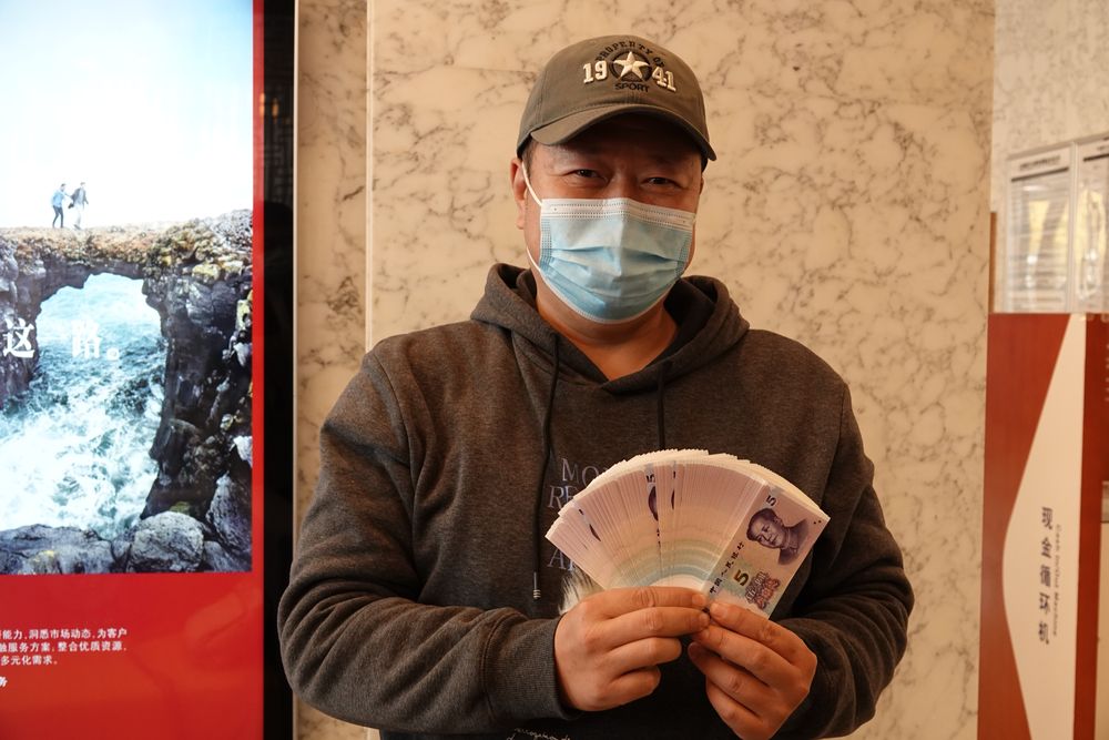 图为5日上午北京市民宋先生通过网点兑换新版5元纸币