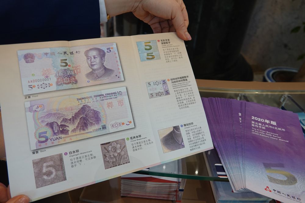 图为交通银行北京市分行营业部一名工作人员展示新版5元纸币的宣传册