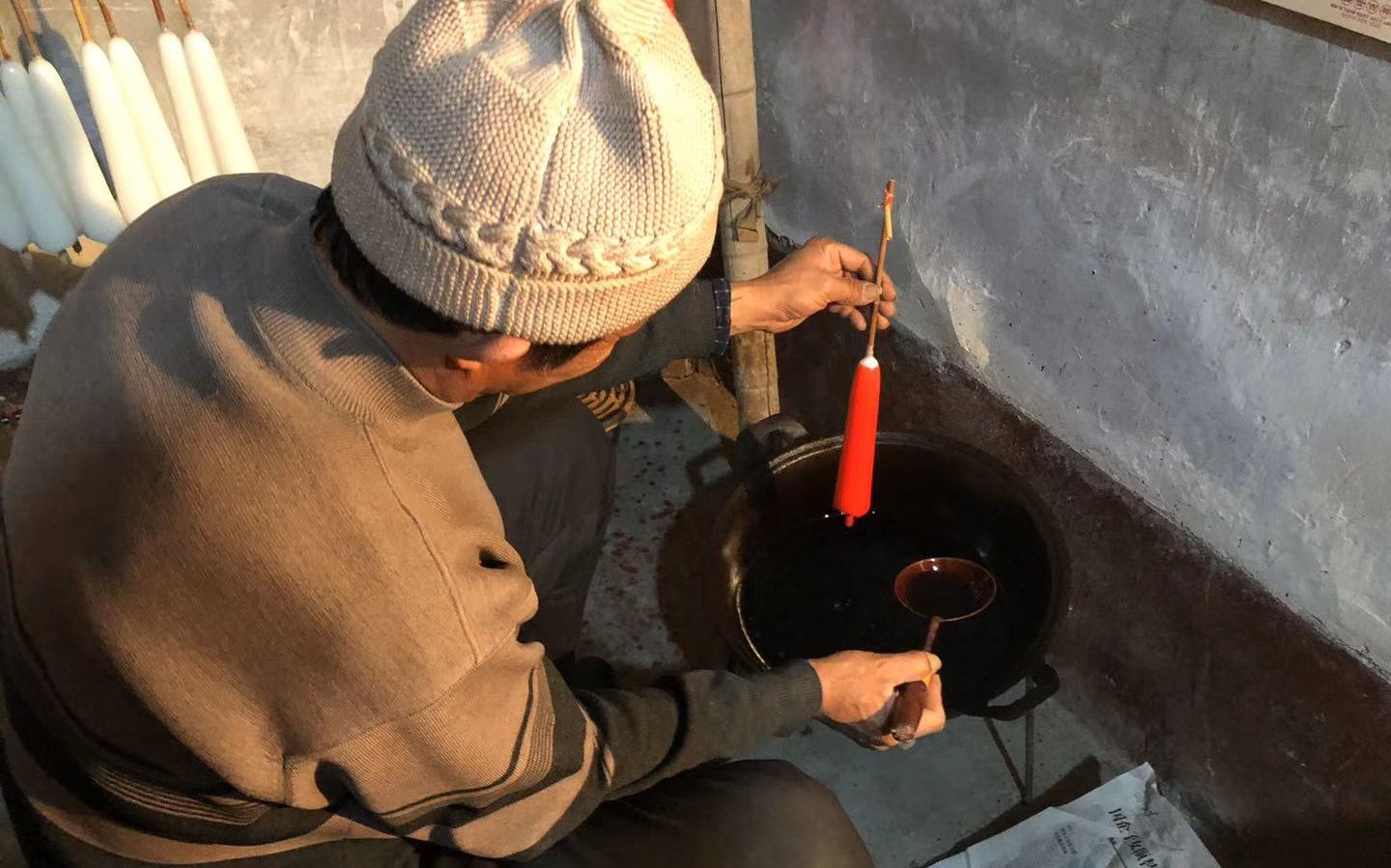 李常胜拿着一根晾干的蜡烛,他将盛有颜料的勺子对准蜡烛底部,一边浇下