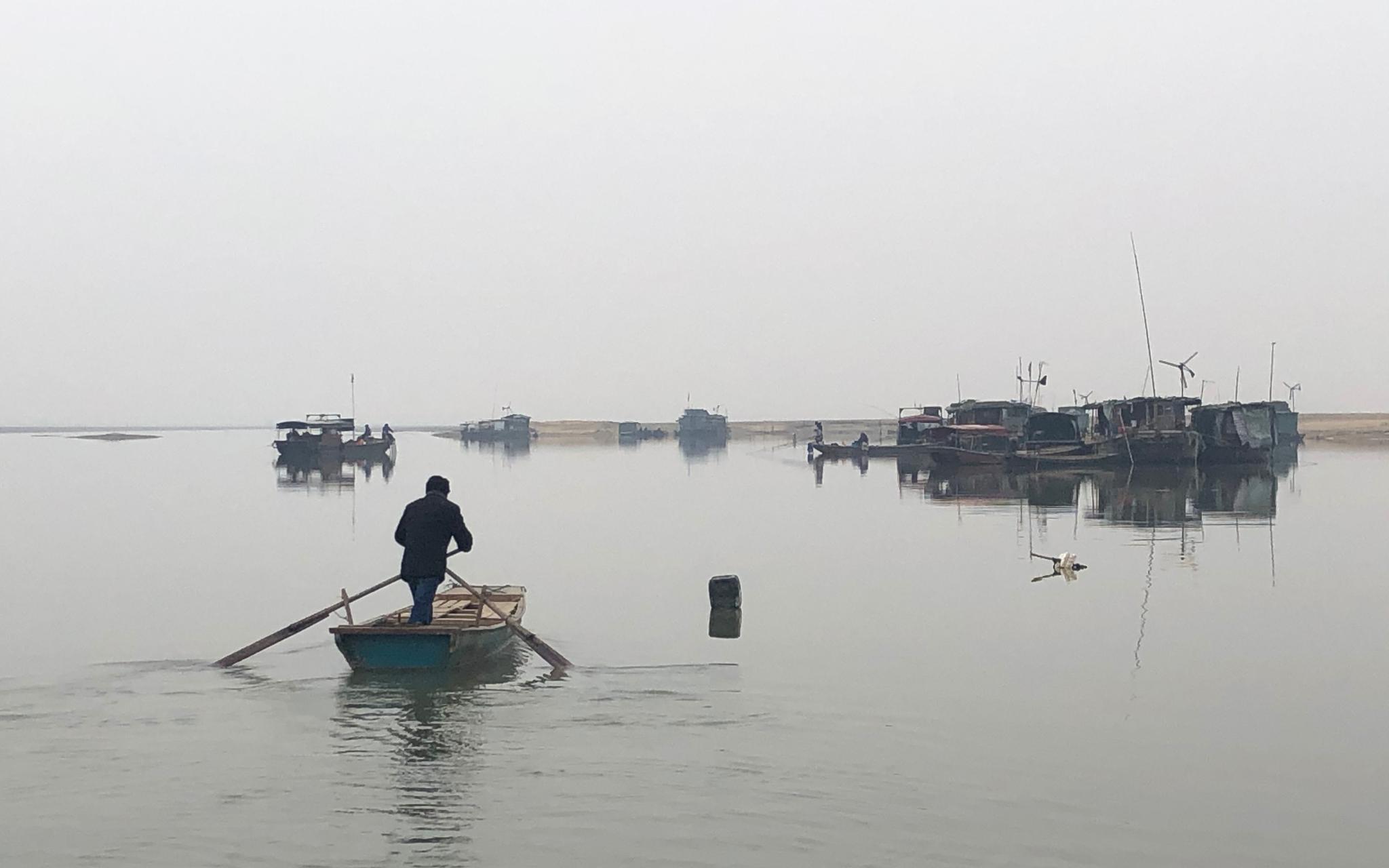 渔民划着小木船驶向停在湖中的生活船。新京报记者 韩沁珂 摄