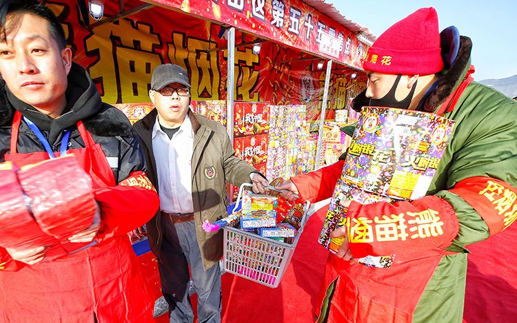 石景山区烟花爆竹零售点,销售人员帮助市民搬运购买的烟花爆竹.