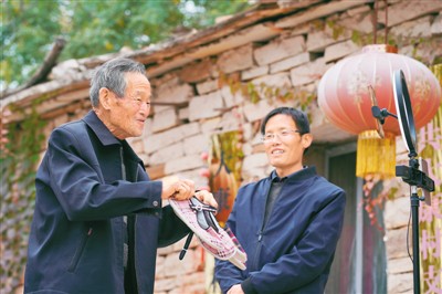 　李三平（左）在直播中推介村民手工制作的布鞋。