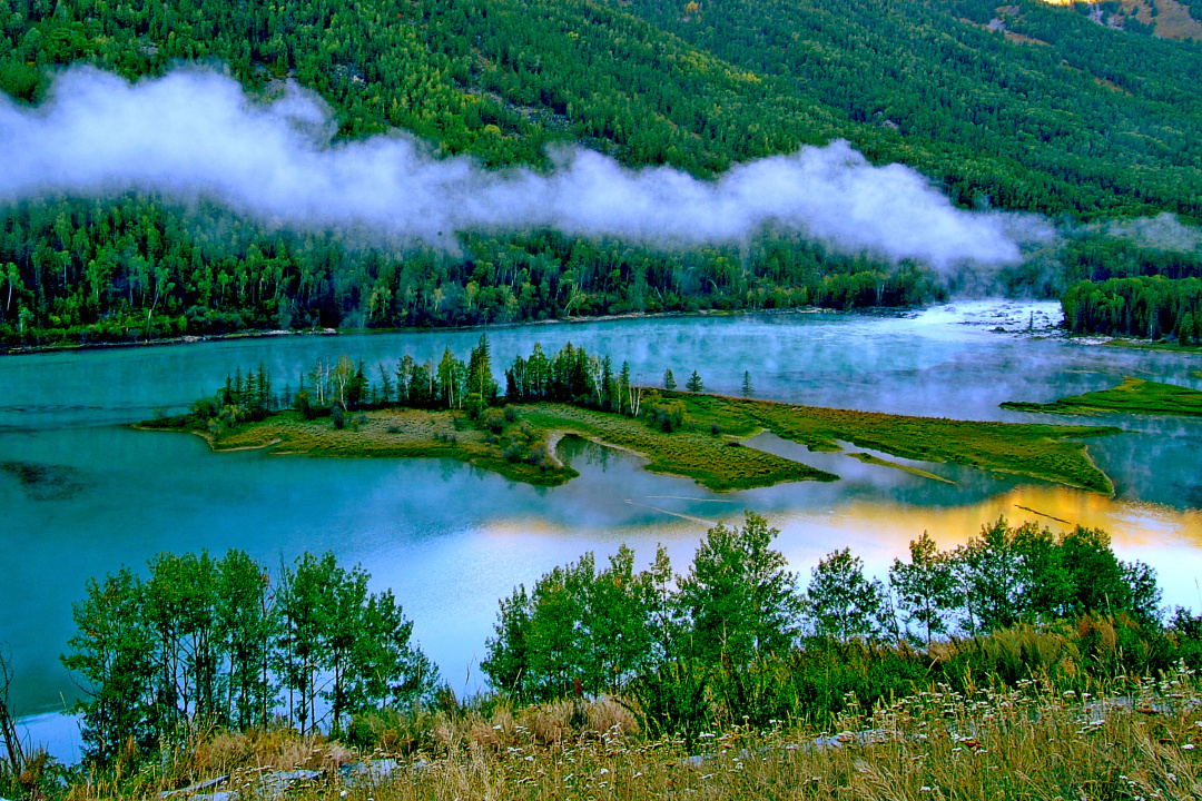升腾起一片片云雾夏天的阳光照在喀纳斯湖面之上经过了初春的新生它就