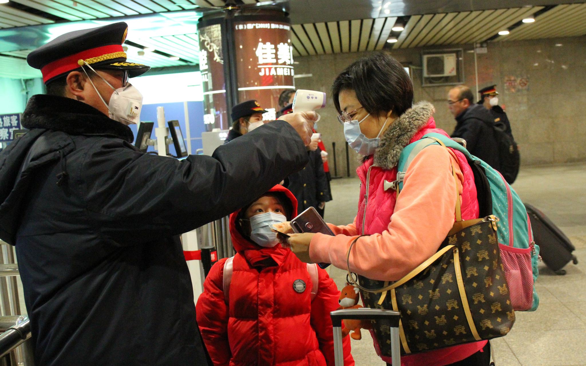 北京西站，工作人员正在用手持额温枪为旅客进行体温测试。北京西站供图