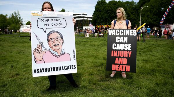 今年5月在华盛顿，两名示威者展示反疫苗标语。（法新社）