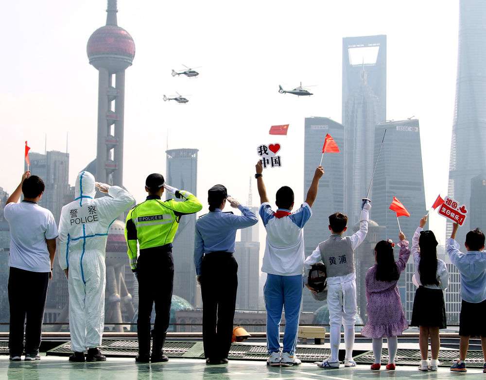 10月1日,警用直升机悬挂着五星红旗飞过上海黄浦江上空。新华社记者 陈飞 摄