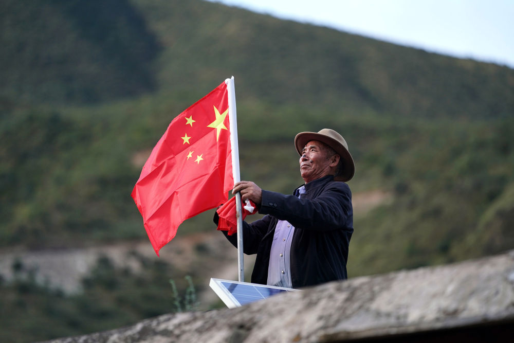 9月25日,在西藏昌都市江达县岗托村,普巴在屋顶上换上崭新的国旗,这是他每月进行一次的“仪式”。今年是昌都解放70周年,普巴说,现在我们的美好日子,是解放军用生命和鲜血换来的,这份恩情,我们不会忘记。新华社记者 詹彦 摄