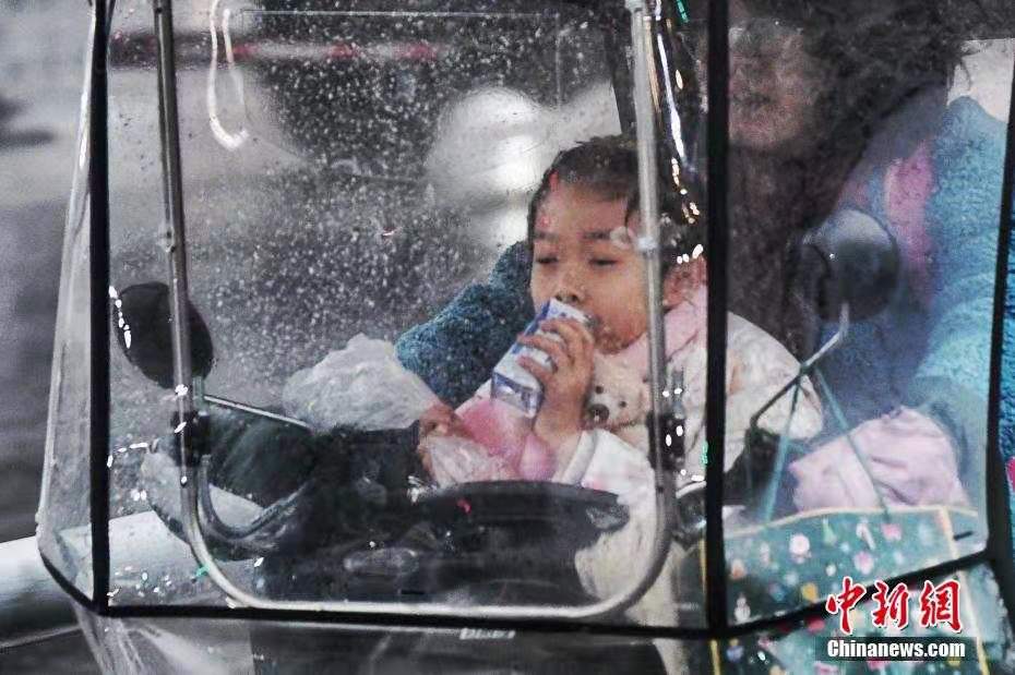受强冷空气影响,我国中东部大部地区将有大风和强降温天气。风雪席卷安徽,气温出现“断崖式”下跌。图为合肥市民在送孩子上学。