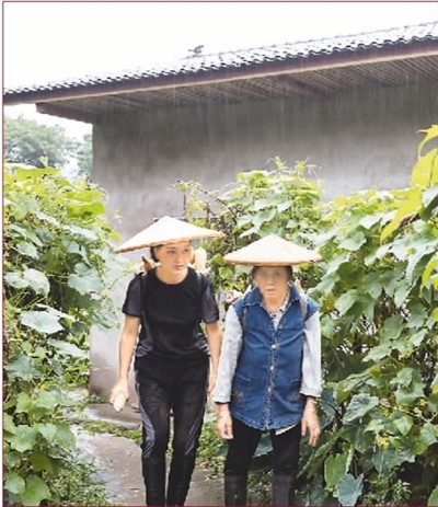 　　何文芳（左）冒雨帮村民背苞谷回家。　　毛晓初摄