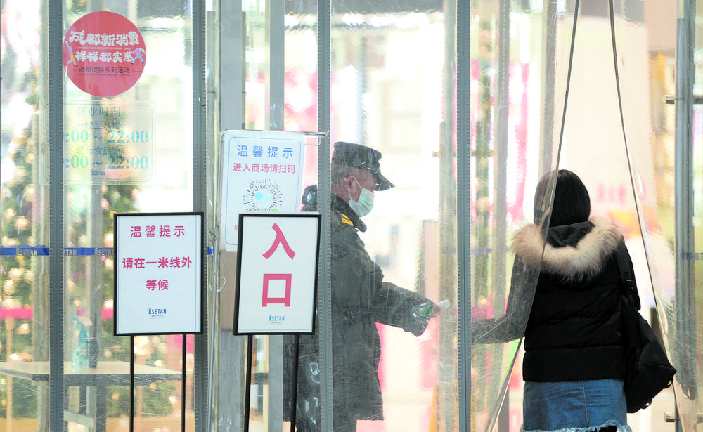 春熙路的一家商场外,安保人员为入店人员测量体温