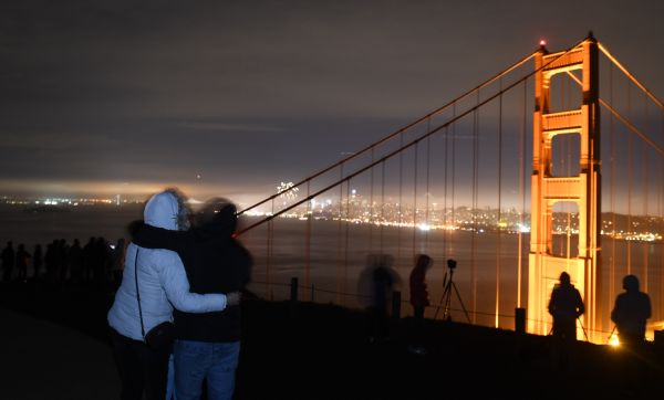 资料图：人们在美国旧金山金门大桥附近远眺焰火。（新华社）