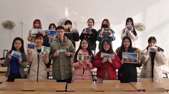 刘馨彤（前排左二）与同学们手持永兴岛明信片和照片合影。