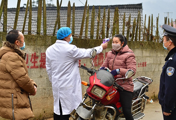突发事件检验基层的治理水平与治理能力。图为2月4日,工作人员在广西融水苗族自治县杆洞乡党鸠村给过往的村民测量体温。新华社 图