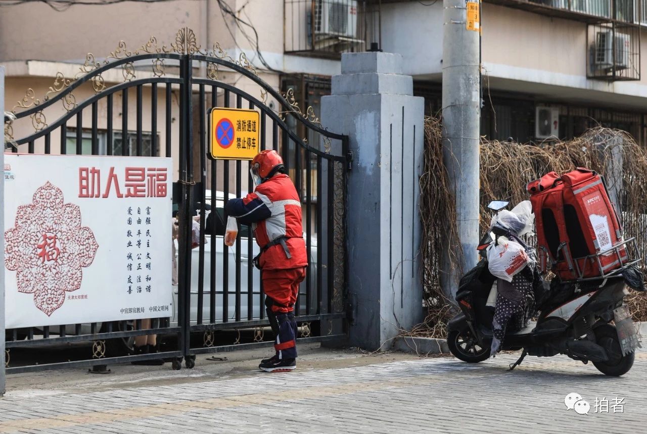 △ 2月3日，海淀区，一名外卖员在给封闭管理的小区居民送餐。摄影/新京报记者浦峰