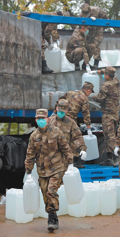 2月10日，河北邯郸市一家爱心组织为火神山医院捐赠的百吨医用消毒原液运抵武汉并予交接，图为医疗队队员在快速搬运医疗物资。　　范显海摄（新华社发）