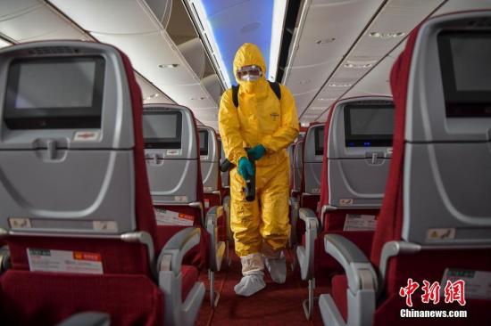 资料图：身着防护服的工作人员对航班客舱进行消毒作业。中新社记者 骆云飞 摄