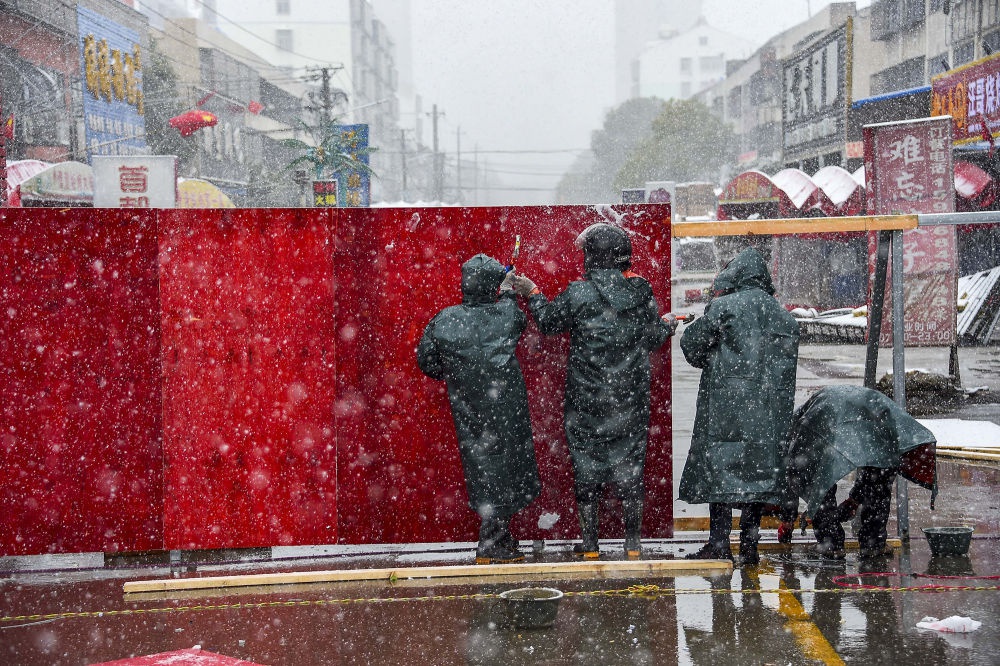 工人在孝南区新华社区加固被大风刮倒的封控设施.