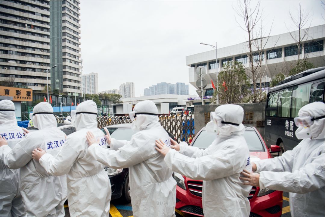 2月11日,一队准备进入武昌方舱医院执勤的民警在防护服外粘贴警察标志。摄影/湖北日报 魏铼