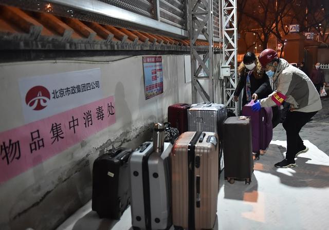 2月20日，工作人员协助返岗务工人员把行李运至物品集中消毒处。新华社发（陈钟昊 摄）