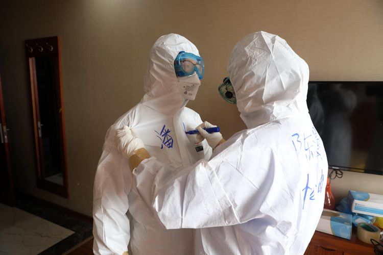 潘恒医生和陈漫怡护士穿好全套防护服出发前,同事在他俩身上写上名字.